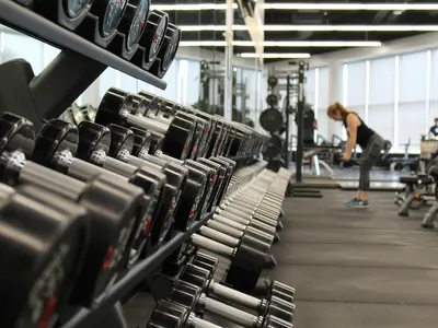 Dumbbell racks with a woman training in the background