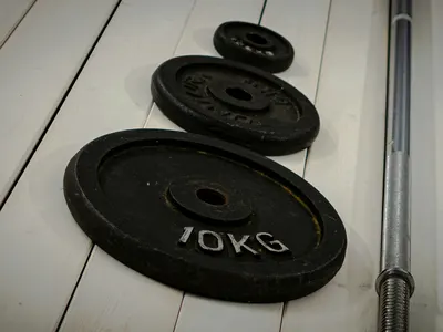 Iron weight plates and a barbell on the floor
